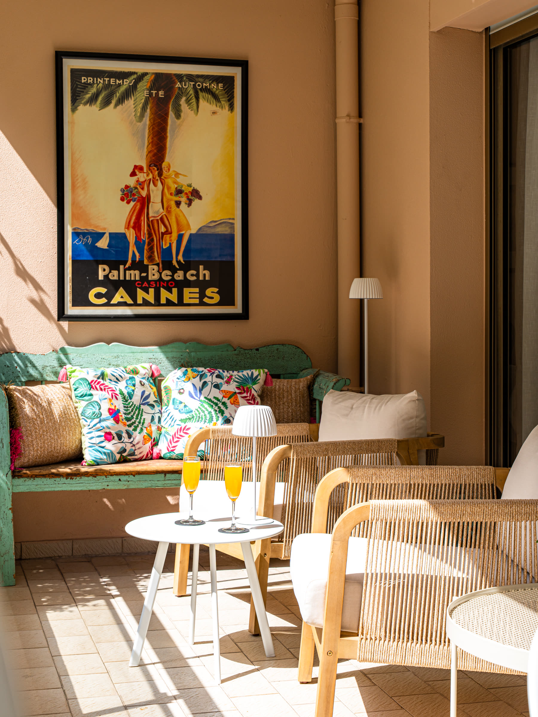 Garden terrace with Palm Beach Cannes poster and lounge seating